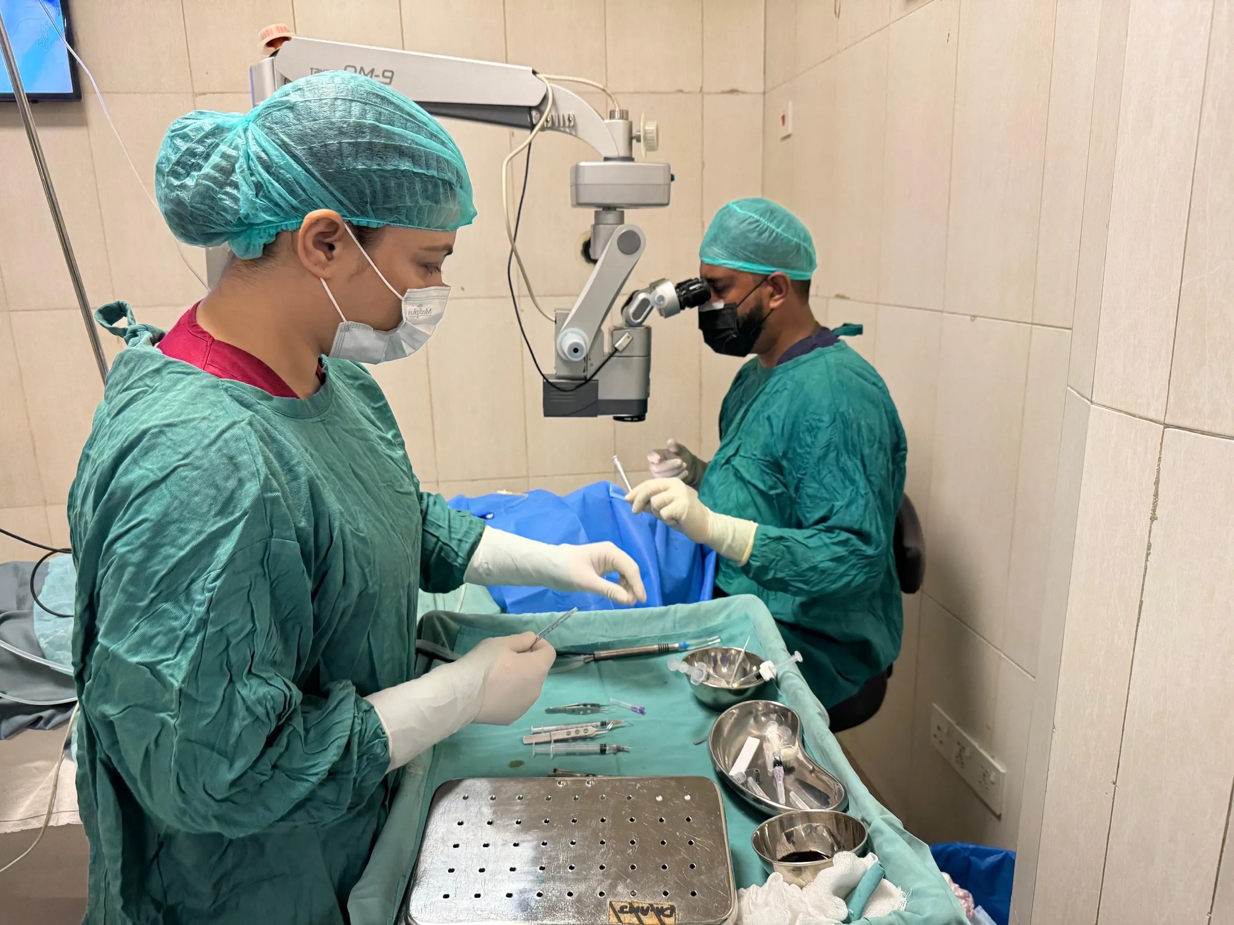 Scrub nurse and surgeon at work during a funded cataract list